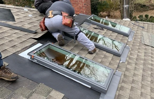 Roofing contractor repairing a leaking skylight on a residential roof.